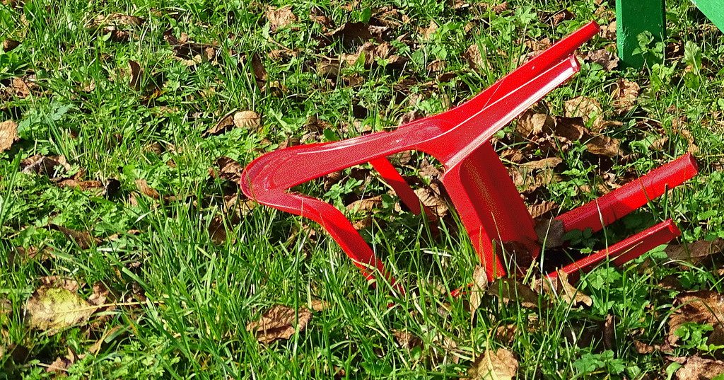ein roter Stuhl der umgefallen in der Wiese liegt