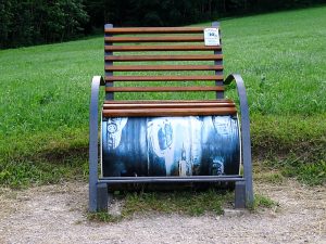 Dieses Bankerl heißt Schoastrommebank. Sie hat am oberen Teil ein Holzlehne und -bank. Darunter liegt quer eine bemalte Tonne