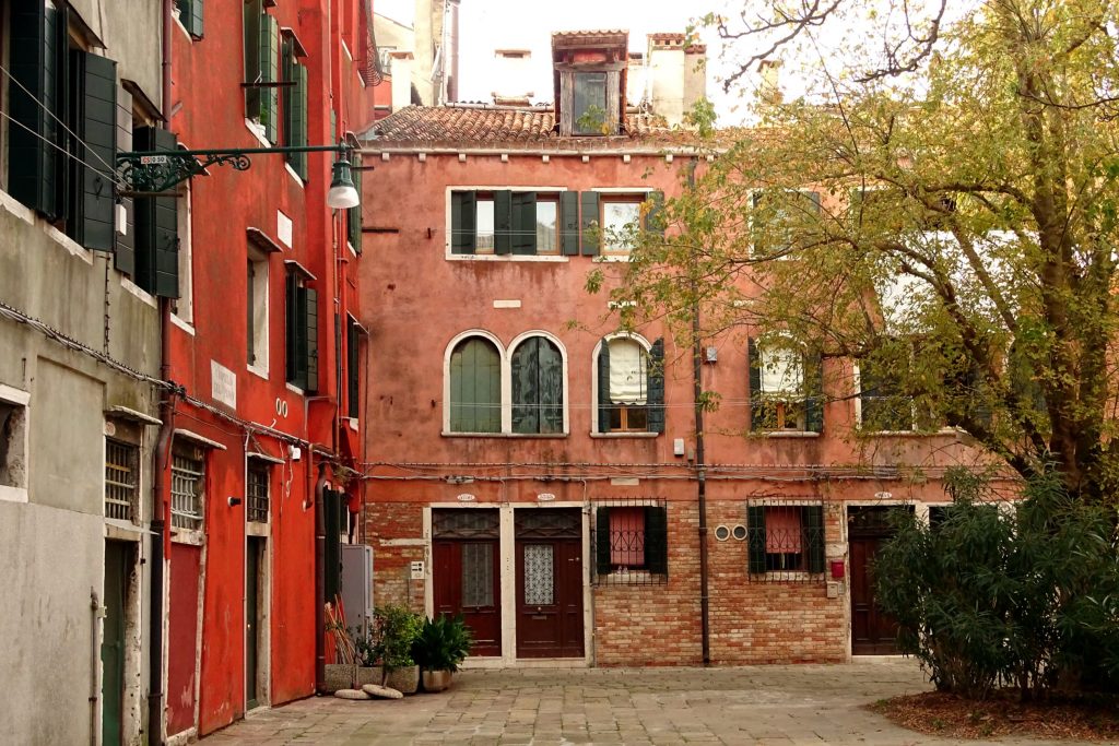 rote Fassaden von Häusern auf dem Platz in Venedig, wo die Bänke stehen